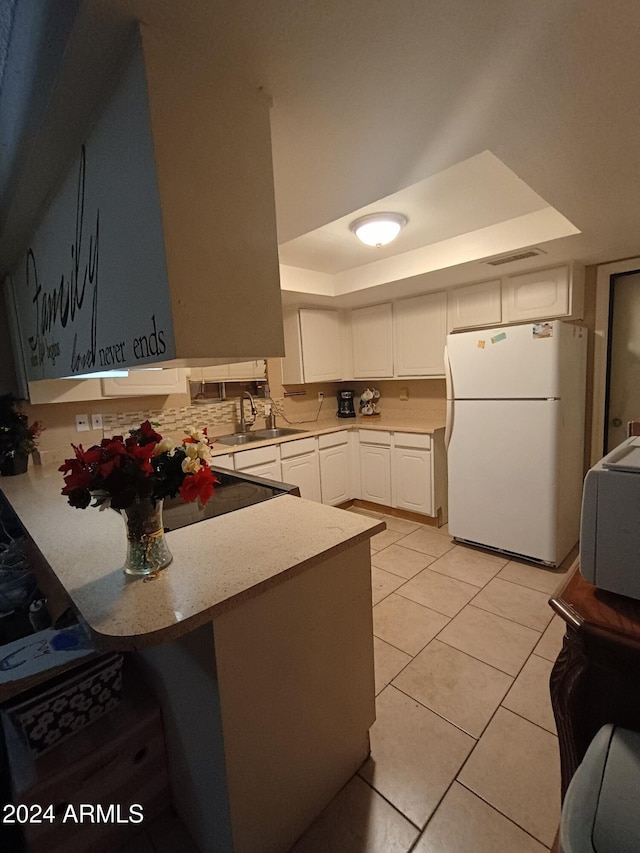 kitchen featuring kitchen peninsula, a raised ceiling, sink, white refrigerator, and white cabinets