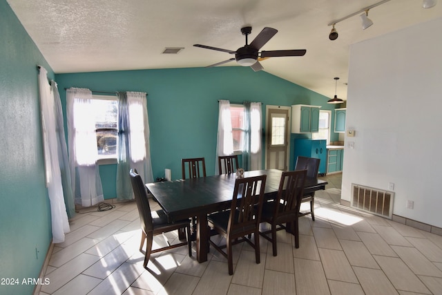 dining area with a textured ceiling, ceiling fan, rail lighting, and lofted ceiling