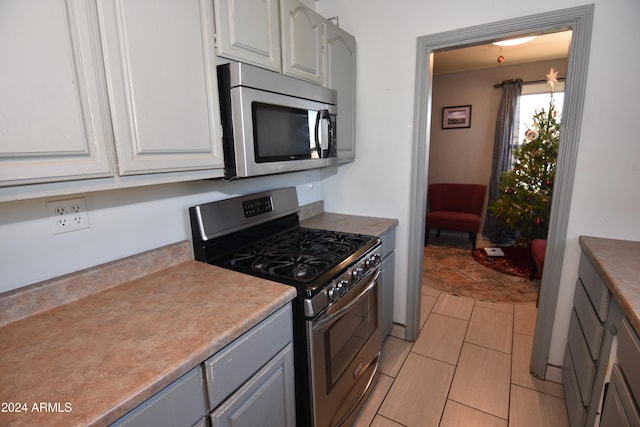 kitchen with gray cabinetry, white cabinetry, and appliances with stainless steel finishes