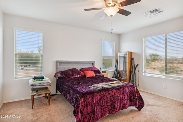 bedroom featuring multiple windows, ceiling fan, and light carpet