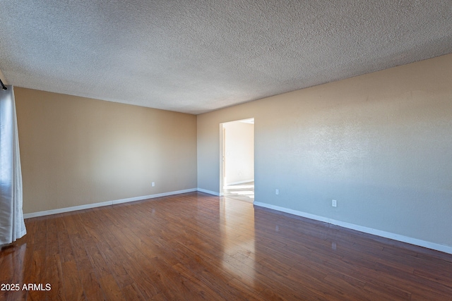 spare room featuring a textured ceiling and dark hardwood / wood-style floors