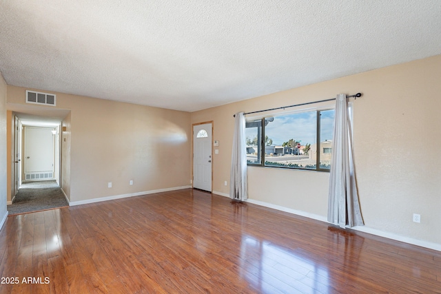 unfurnished room with hardwood / wood-style floors and a textured ceiling