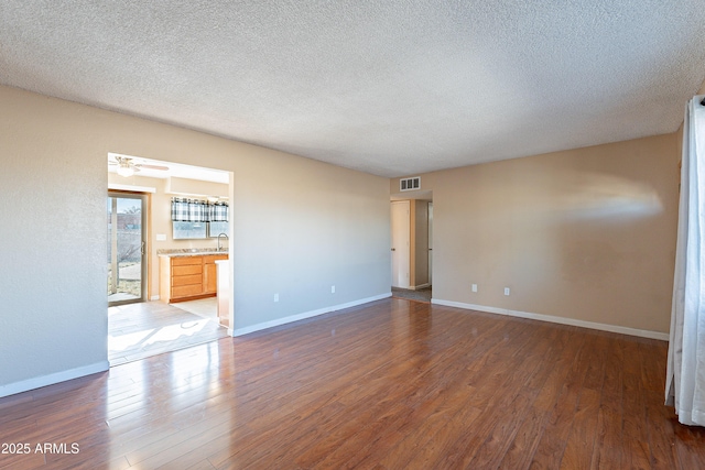 spare room with ceiling fan, sink, dark wood-type flooring, and a textured ceiling