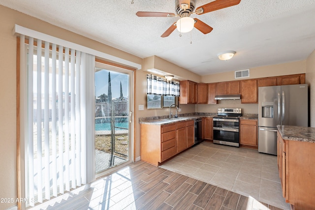 kitchen with a textured ceiling, sink, stainless steel appliances, and plenty of natural light