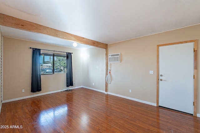 unfurnished room with hardwood / wood-style flooring, beam ceiling, and a wall mounted AC