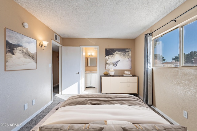 bedroom featuring ensuite bath, sink, carpet, and a textured ceiling