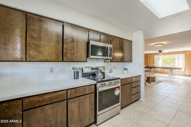 kitchen featuring tasteful backsplash, dark brown cabinetry, appliances with stainless steel finishes, and light tile patterned floors