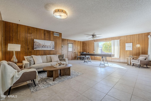 living room with light tile patterned floors, a textured ceiling, and wood walls