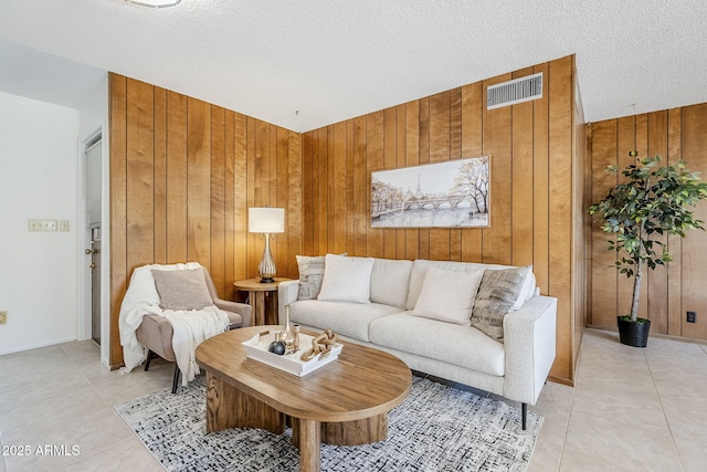 living room with light tile patterned flooring, wooden walls, and a textured ceiling