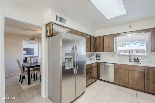 kitchen with sink, backsplash, light tile patterned flooring, and appliances with stainless steel finishes