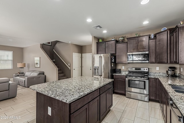 1723 N Hillcrest, Mesa, AZ 85201 - kitchen featuring stainless steel appliances, open floor plan, dark brown cabinetry, light stone countertops, and a kitchen island