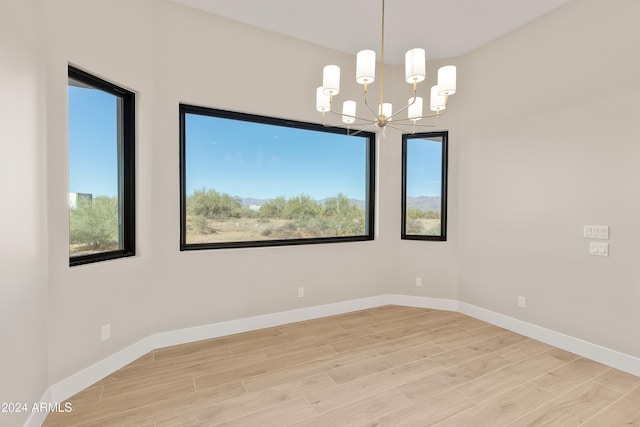 unfurnished room with light hardwood / wood-style floors and an inviting chandelier