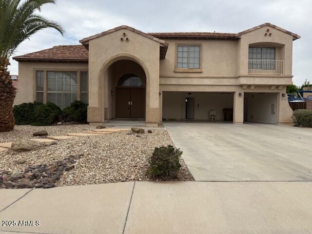 mediterranean / spanish-style house with an attached garage, concrete driveway, and stucco siding