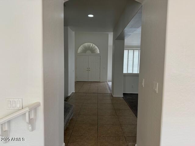 hall with dark tile patterned floors, baseboards, and recessed lighting