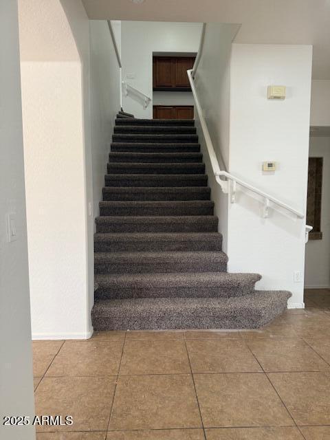 stairway with tile patterned floors and baseboards