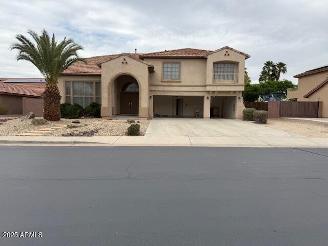 mediterranean / spanish house featuring driveway, a garage, stucco siding, and fence