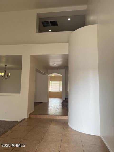 corridor featuring tile patterned floors, visible vents, an inviting chandelier, and baseboards