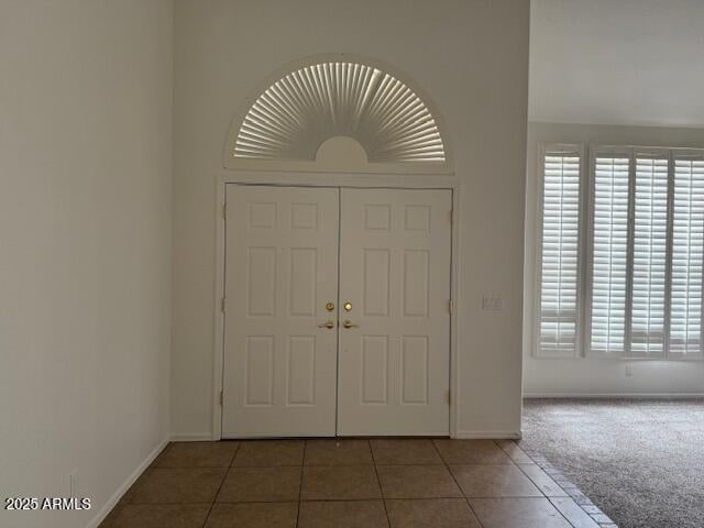 carpeted entryway featuring plenty of natural light, tile patterned floors, and baseboards
