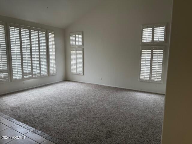 unfurnished room featuring baseboards, vaulted ceiling, and carpet floors