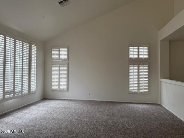 empty room with lofted ceiling, carpet, visible vents, and baseboards