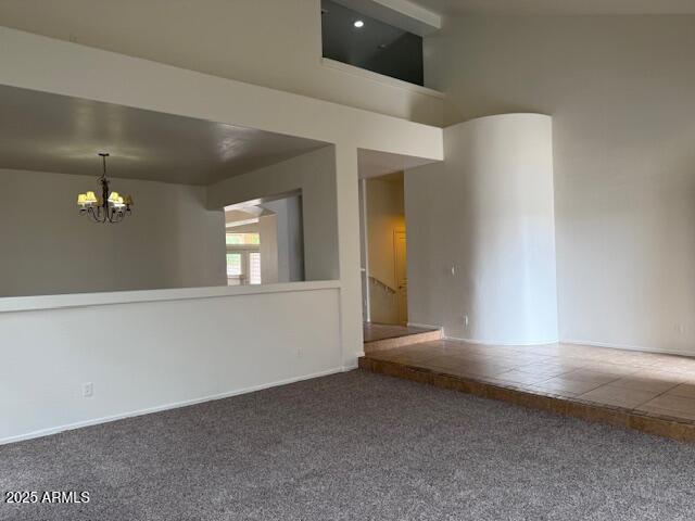 spare room featuring a chandelier, a high ceiling, and carpet flooring