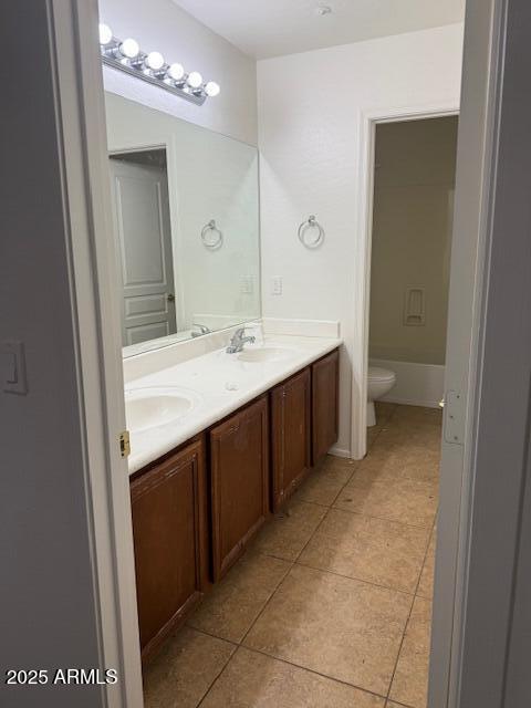 bathroom featuring toilet, tile patterned flooring, a sink, and double vanity