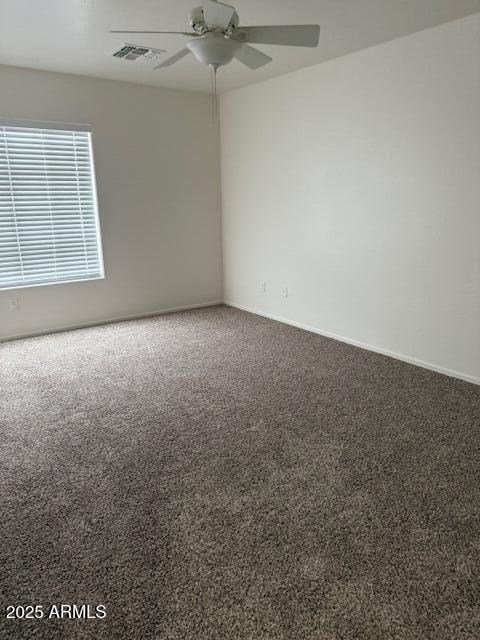 empty room with baseboards, visible vents, ceiling fan, and carpet floors