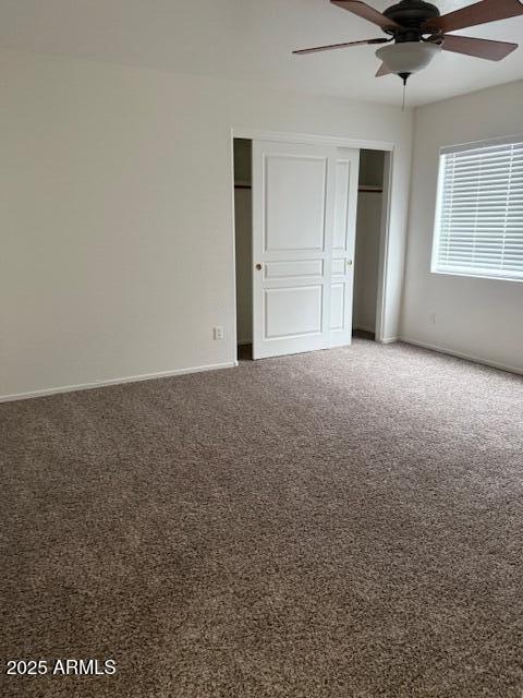 unfurnished bedroom featuring a closet, ceiling fan, carpet floors, and baseboards
