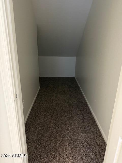 interior space featuring carpet flooring, vaulted ceiling, and baseboards