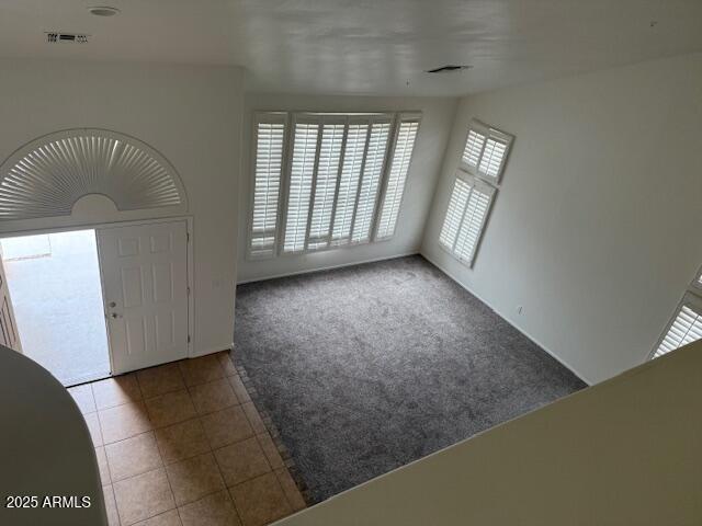 tiled entrance foyer featuring visible vents and carpet floors