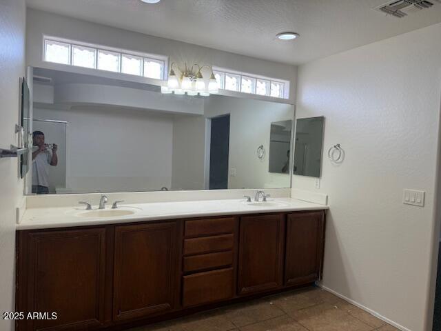 full bathroom with baseboards, visible vents, double vanity, and a sink
