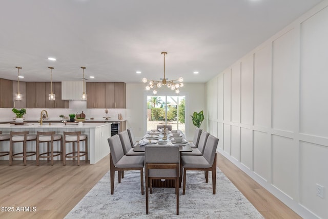 dining space with light wood-style flooring, wine cooler, a decorative wall, and recessed lighting