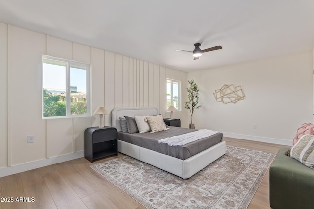 bedroom with light wood finished floors, ceiling fan, multiple windows, and baseboards