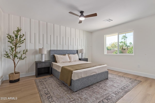 bedroom featuring light wood finished floors, baseboards, visible vents, and ceiling fan