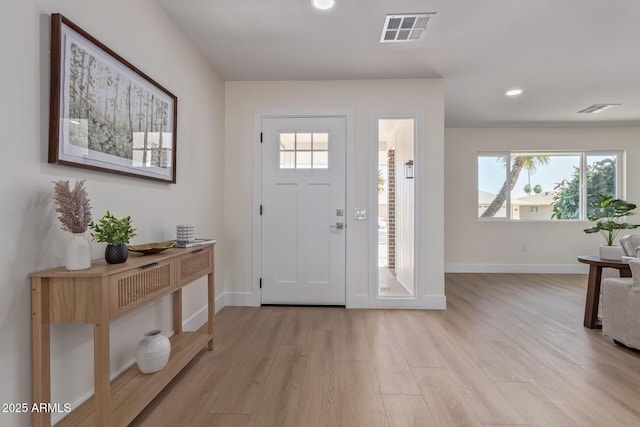 foyer featuring light wood-type flooring, baseboards, and visible vents