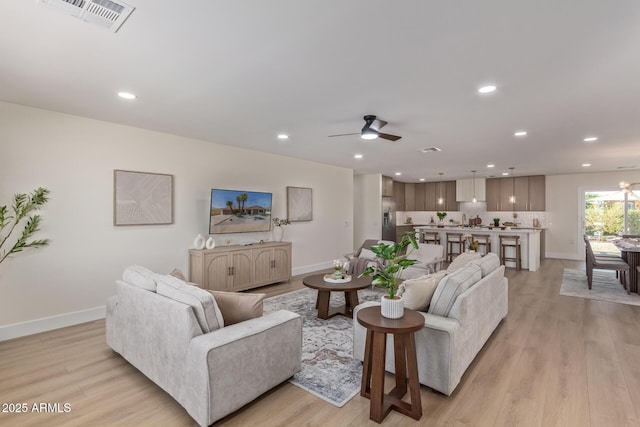 living room with visible vents, baseboards, a ceiling fan, light wood-style flooring, and recessed lighting