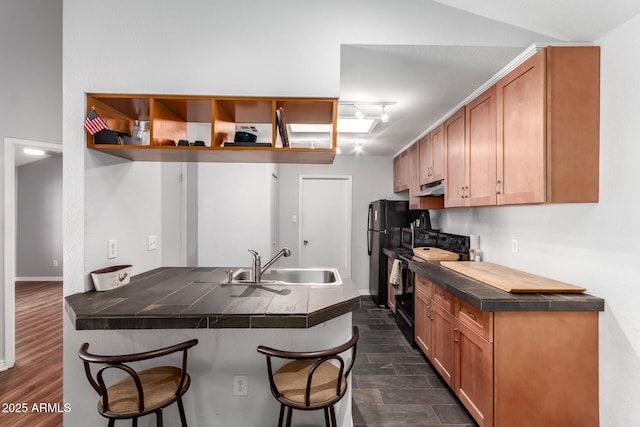 kitchen featuring a breakfast bar, black appliances, sink, tile counters, and kitchen peninsula