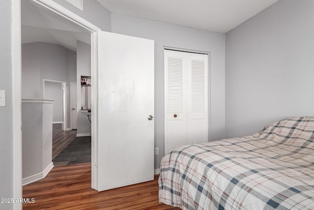 bedroom with vaulted ceiling, dark hardwood / wood-style flooring, and a closet