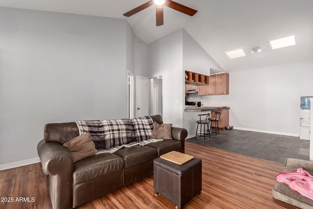 living room with a skylight, ceiling fan, high vaulted ceiling, and dark hardwood / wood-style floors