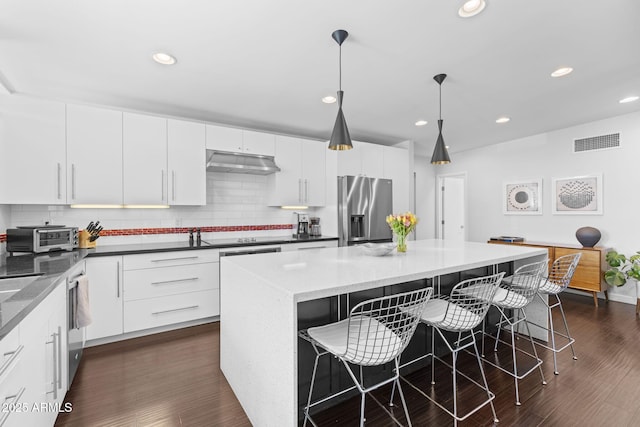 3402 E Sells Dr, Phoenix, AZ 85018 - kitchen with stainless steel appliances, under cabinet range hood, a kitchen breakfast bar, a kitchen island, and white cabinets