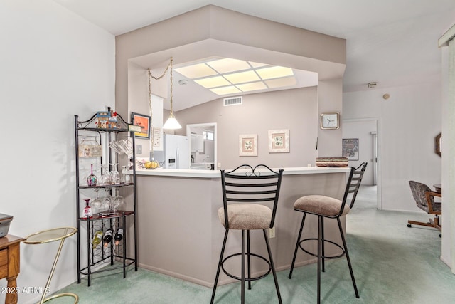 bar with pendant lighting, white refrigerator with ice dispenser, vaulted ceiling, and carpet