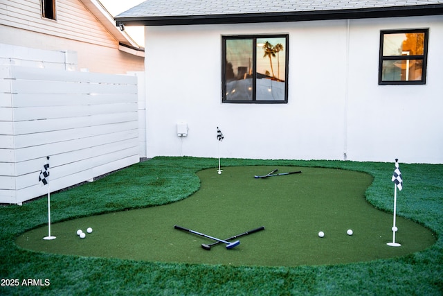 view of home's community with an area to practice putting and fence