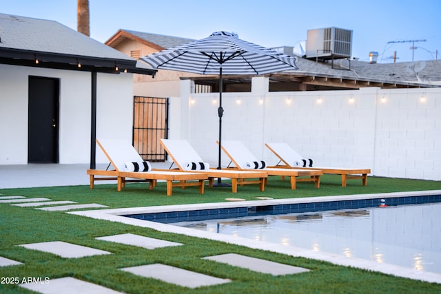 rear view of property featuring central AC unit and a swimming pool