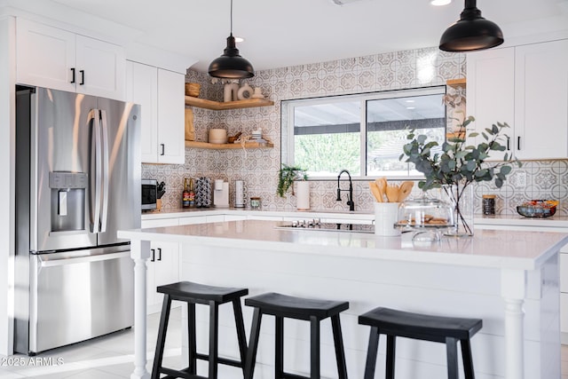 kitchen with appliances with stainless steel finishes, light countertops, backsplash, a kitchen bar, and recessed lighting