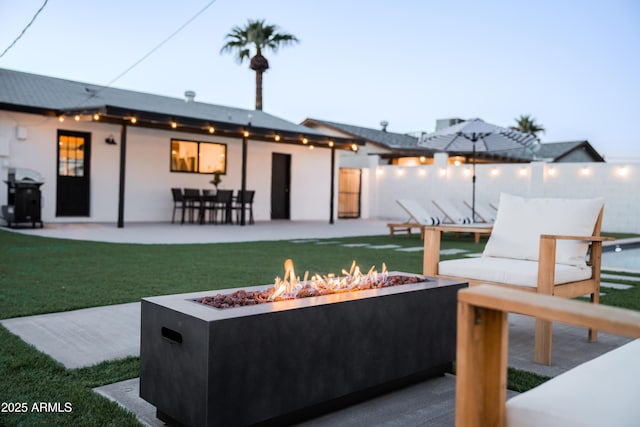 back of house with a fire pit, a patio, and stucco siding