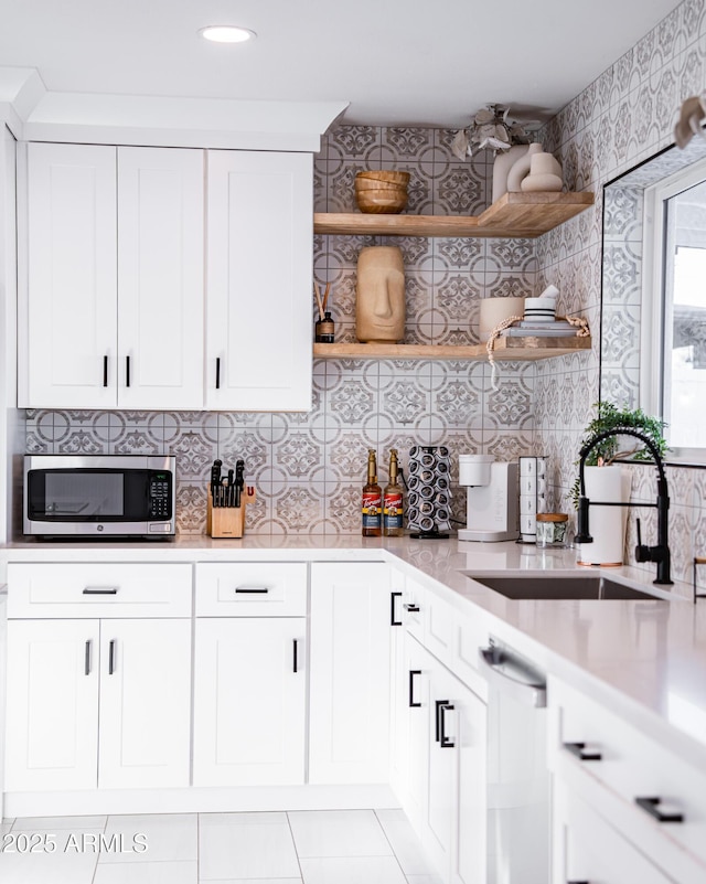 kitchen featuring appliances with stainless steel finishes, open shelves, a sink, light countertops, and recessed lighting