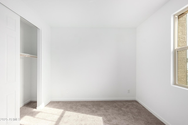 unfurnished bedroom with a closet and light colored carpet