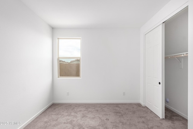 unfurnished bedroom featuring light colored carpet and a closet