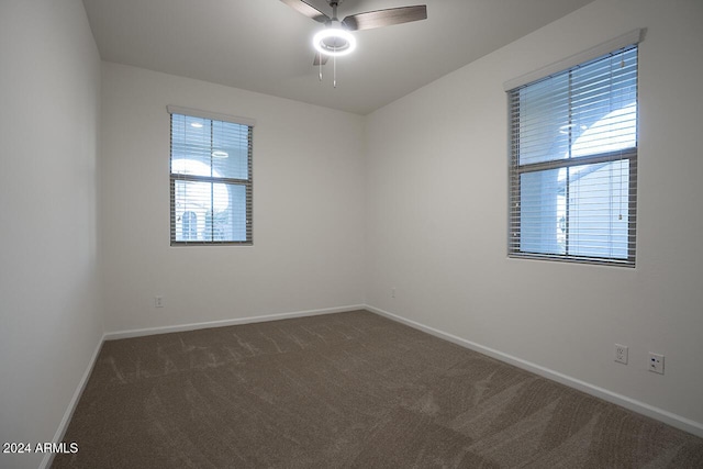 empty room featuring dark colored carpet, plenty of natural light, and ceiling fan