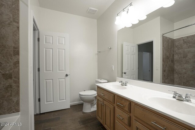 bathroom with vanity, toilet, and tiled shower